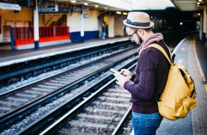 Man waits for train with phone in hand