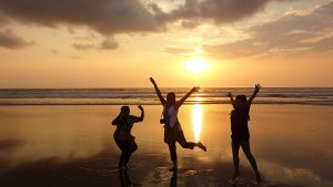 three women jumping under Australia beach sunset