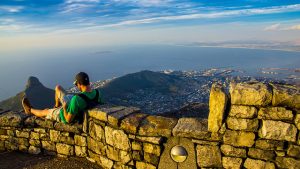 man reading atop table mountain overlooking western cape