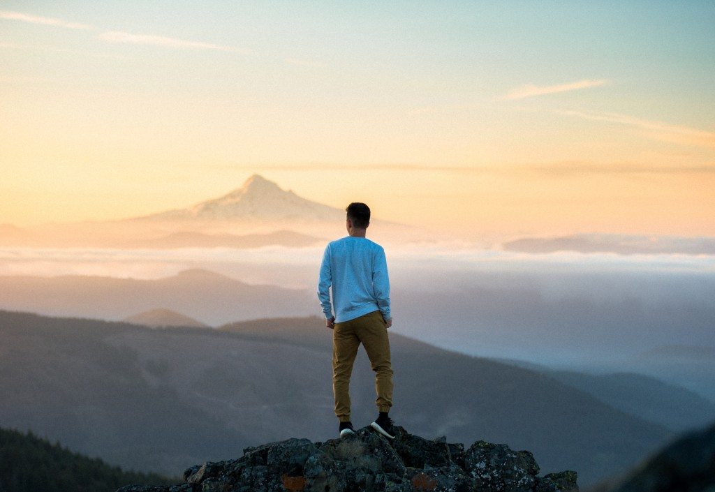 Man standing on top mountain looking at the view